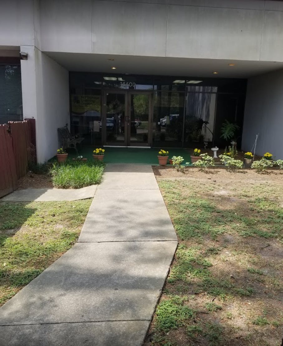 Concrete walkway leading to a building entrance with glass doors