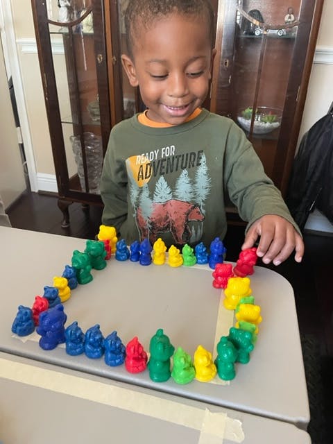 Child playing with colorful bear-shaped counters on a table