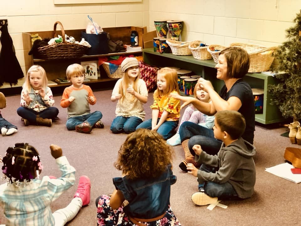 Adult and children sitting in a circle on the floor