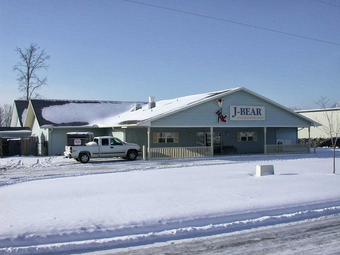 Building with "J-BEAR" sign and a truck in a snowy landscape