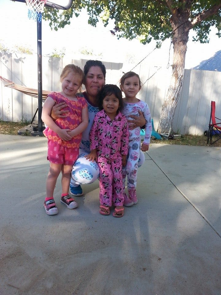 Person kneeling with three children standing around them