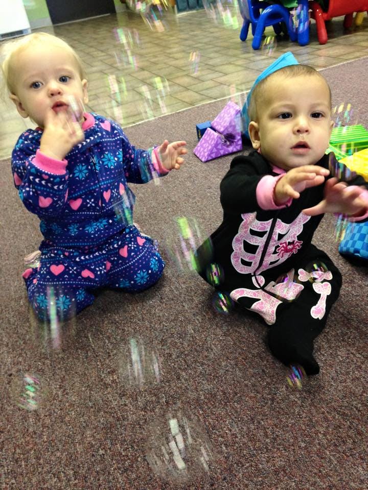 Two children on a carpeted floor with bubbles around them