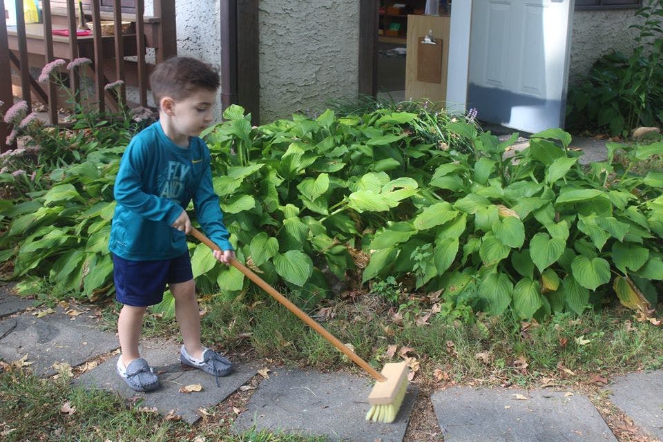 Child sweeping a patio with a broom
