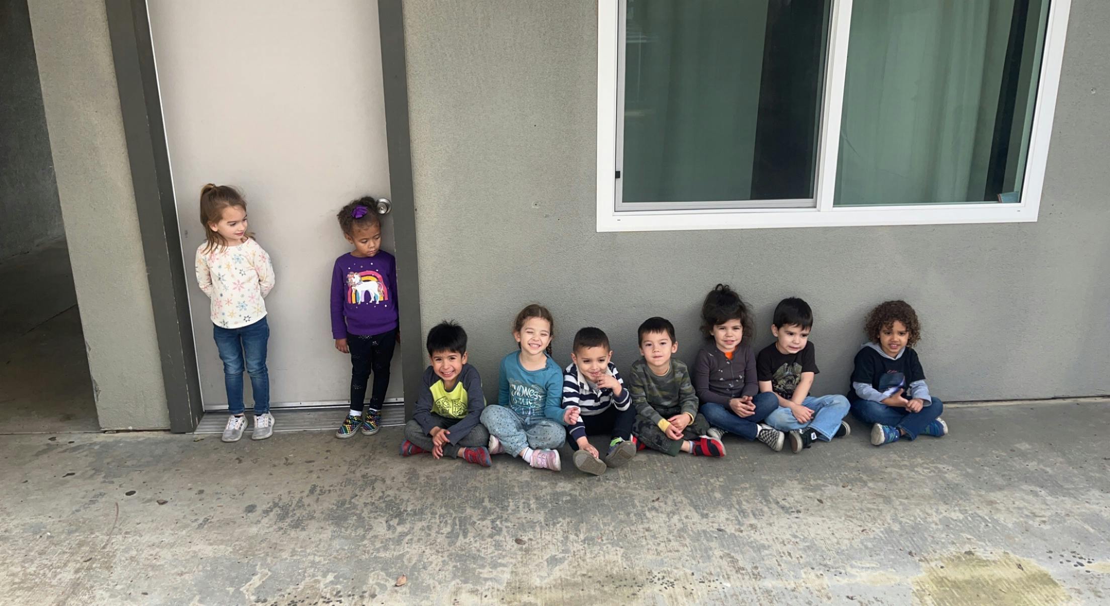 Group of children standing and sitting against a wall