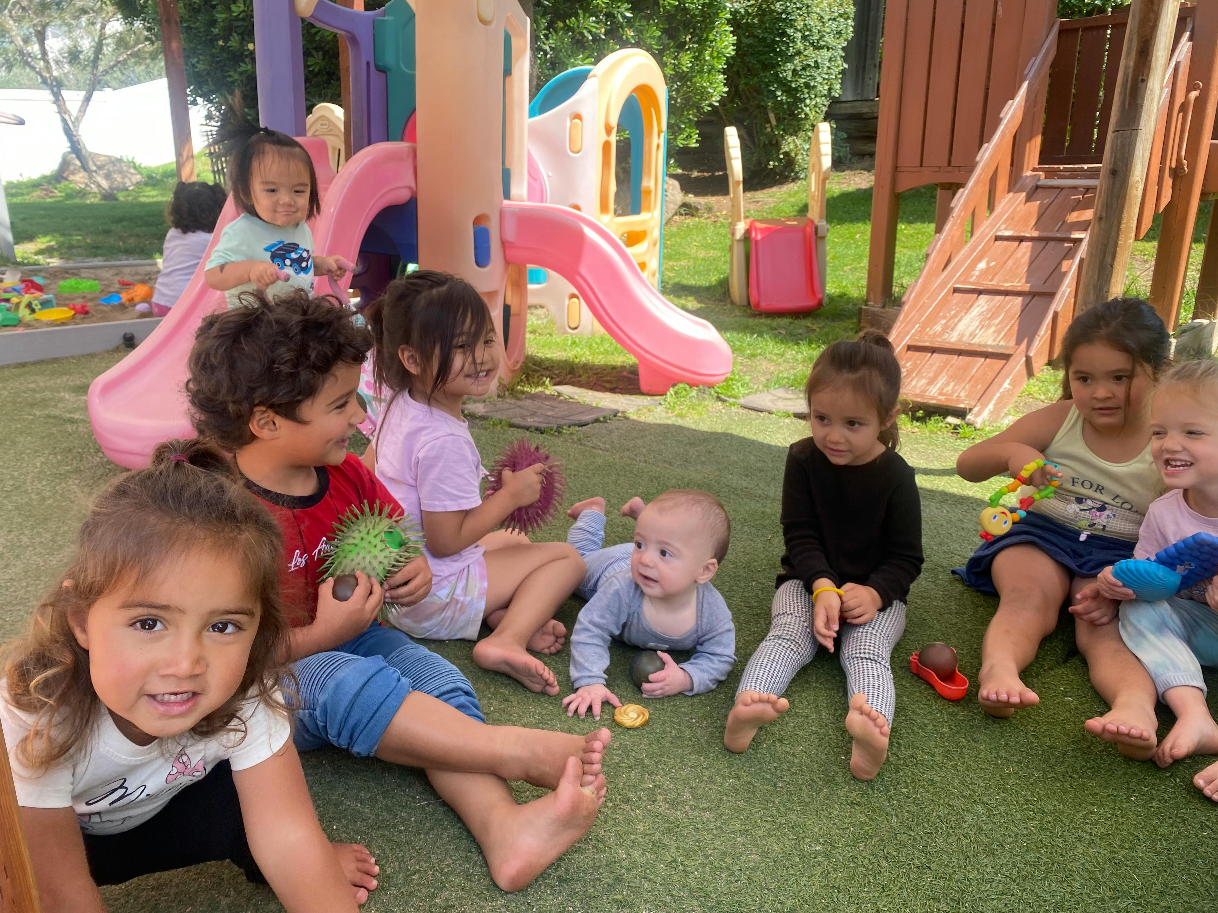 Group of children playing with toys on artificial grass in a playground
