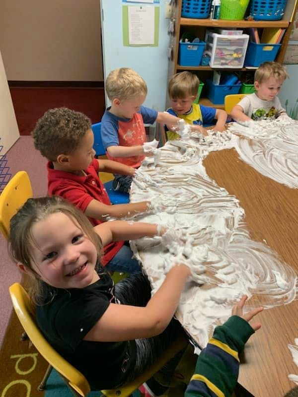 Children playing with shaving cream on a table