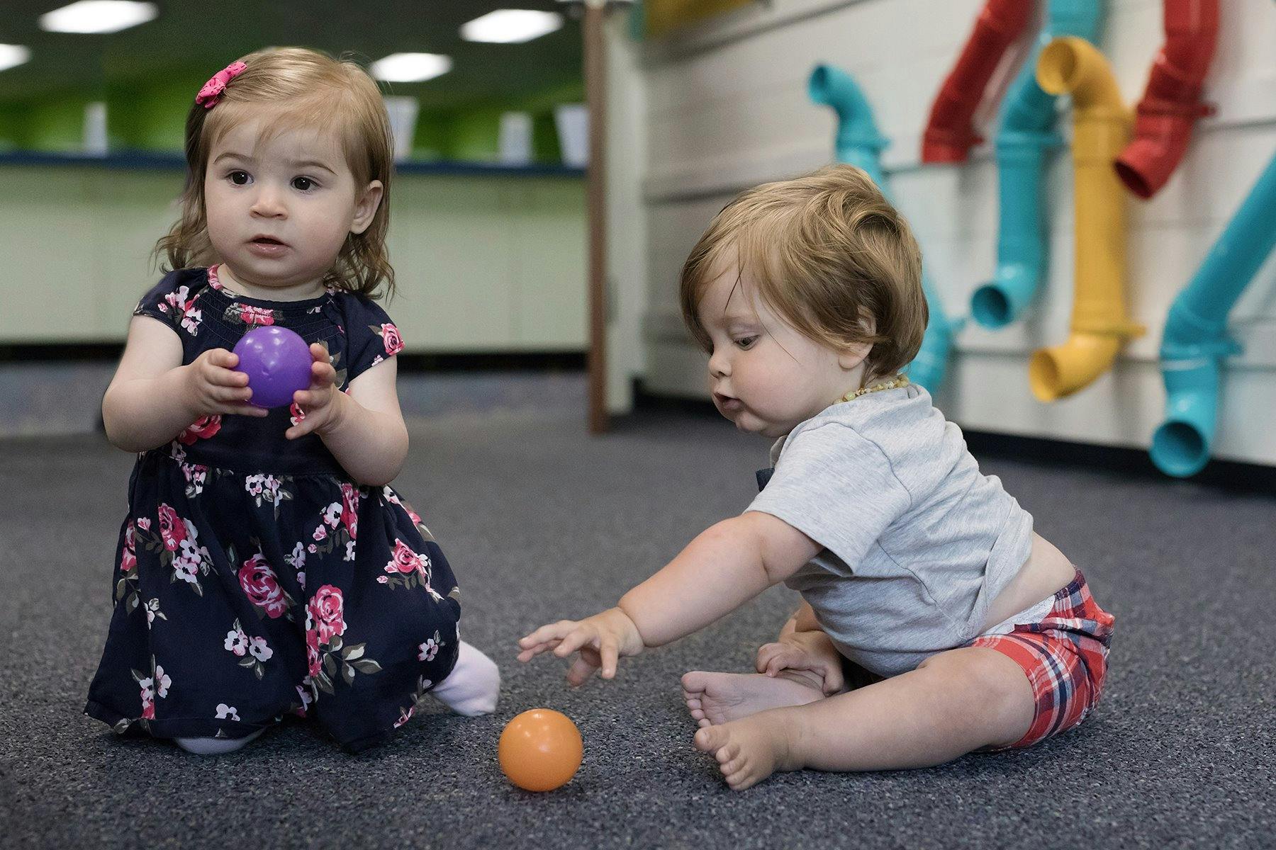 Two children playing with balls on the floor