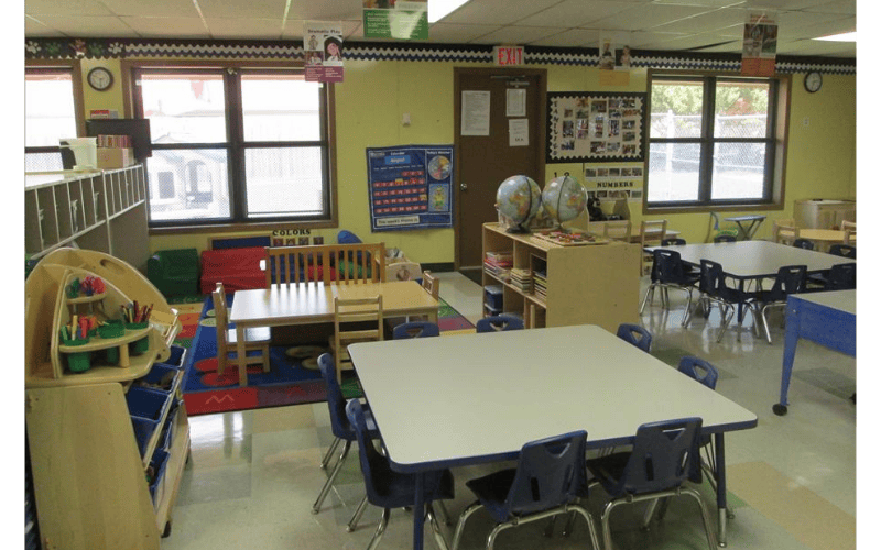 Empty classroom with small tables, chairs, and learning materials