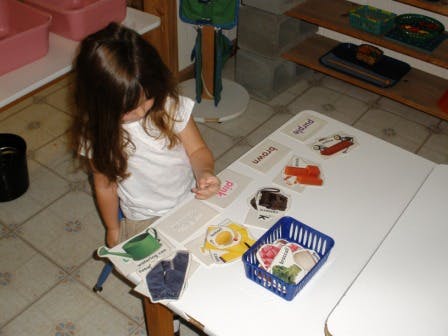 Child at a table with cards and a basket of items