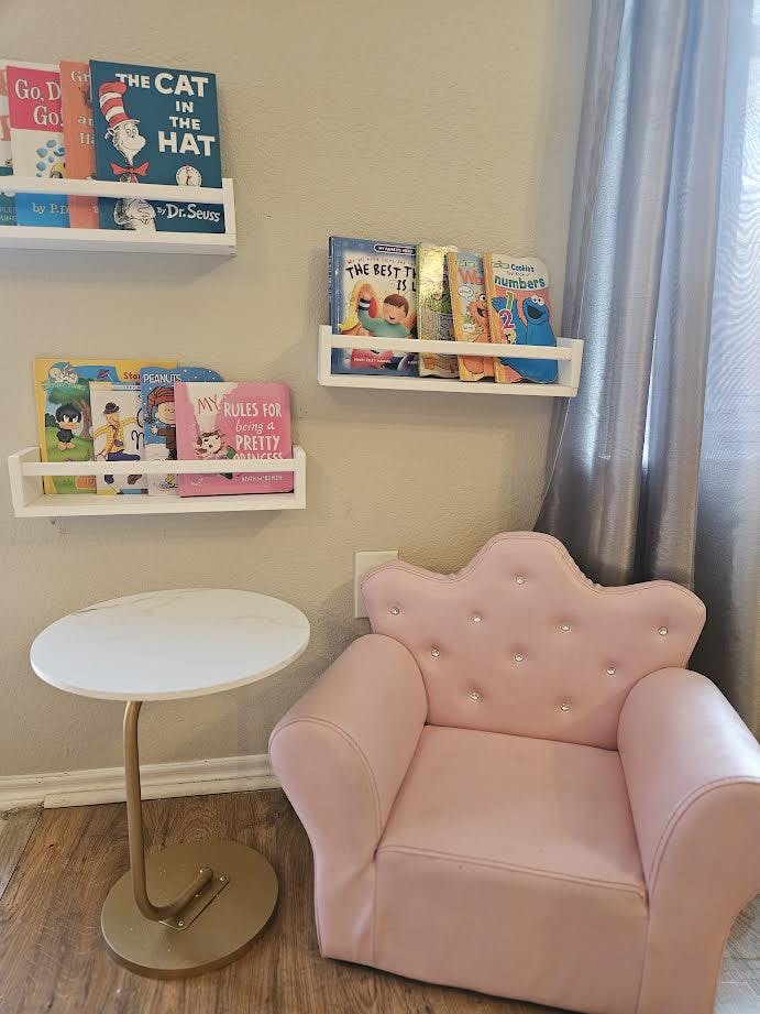 Pink child's armchair next to a small table and bookshelves