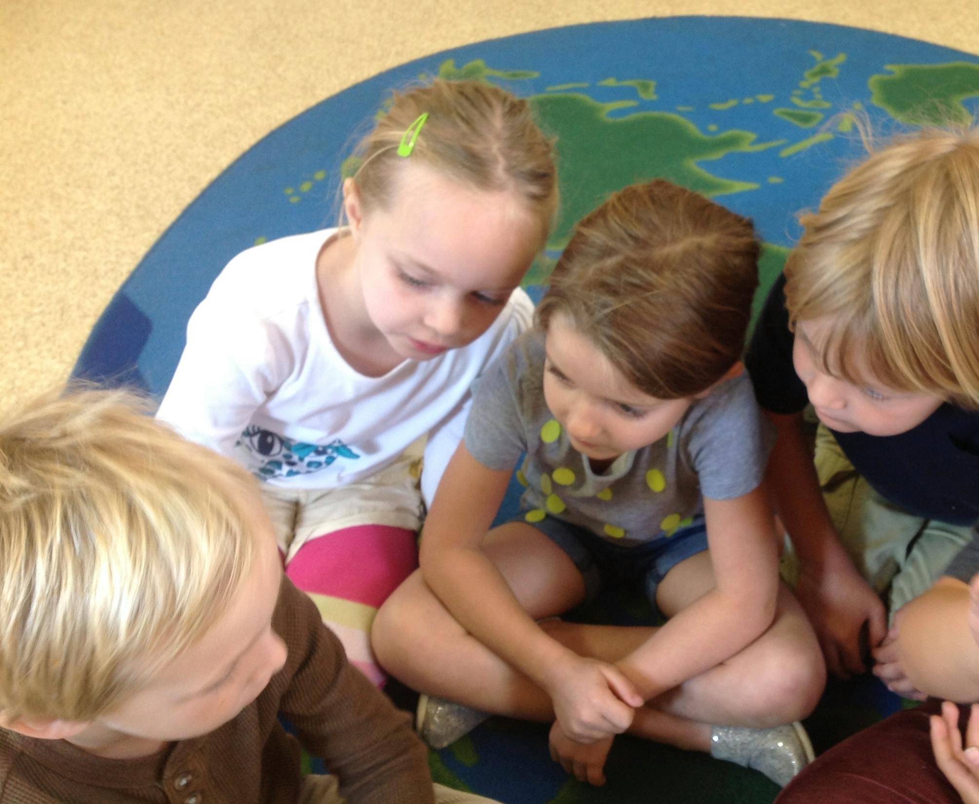 Four children looking down at a map on the floor