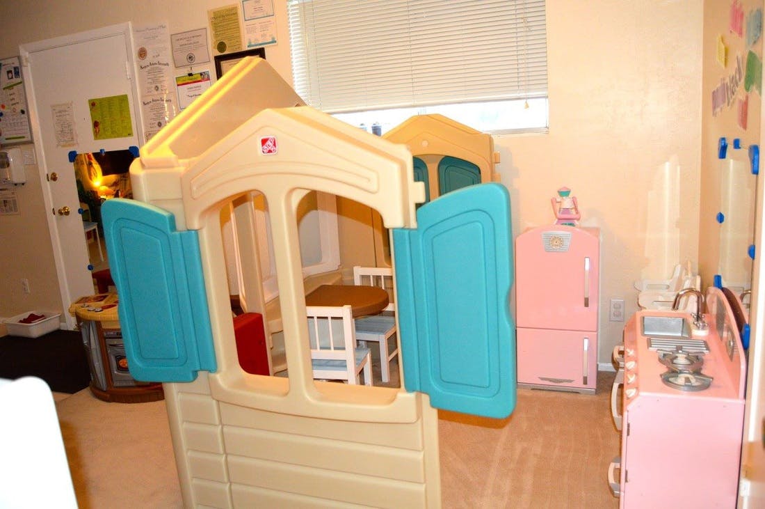 Playhouse with blue shutters and toy kitchen in a room