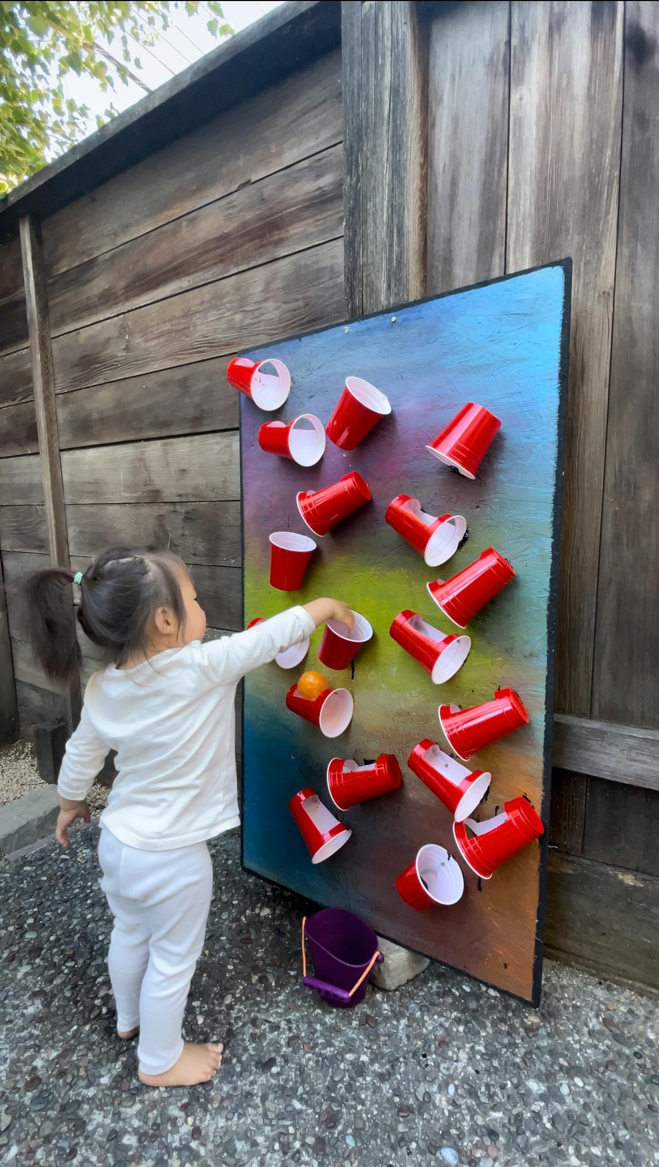 Child playing with red cups on a board