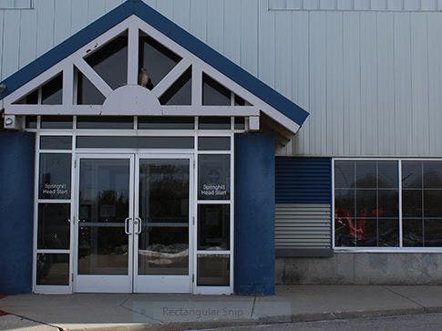 Building entrance with glass doors and a peaked roof