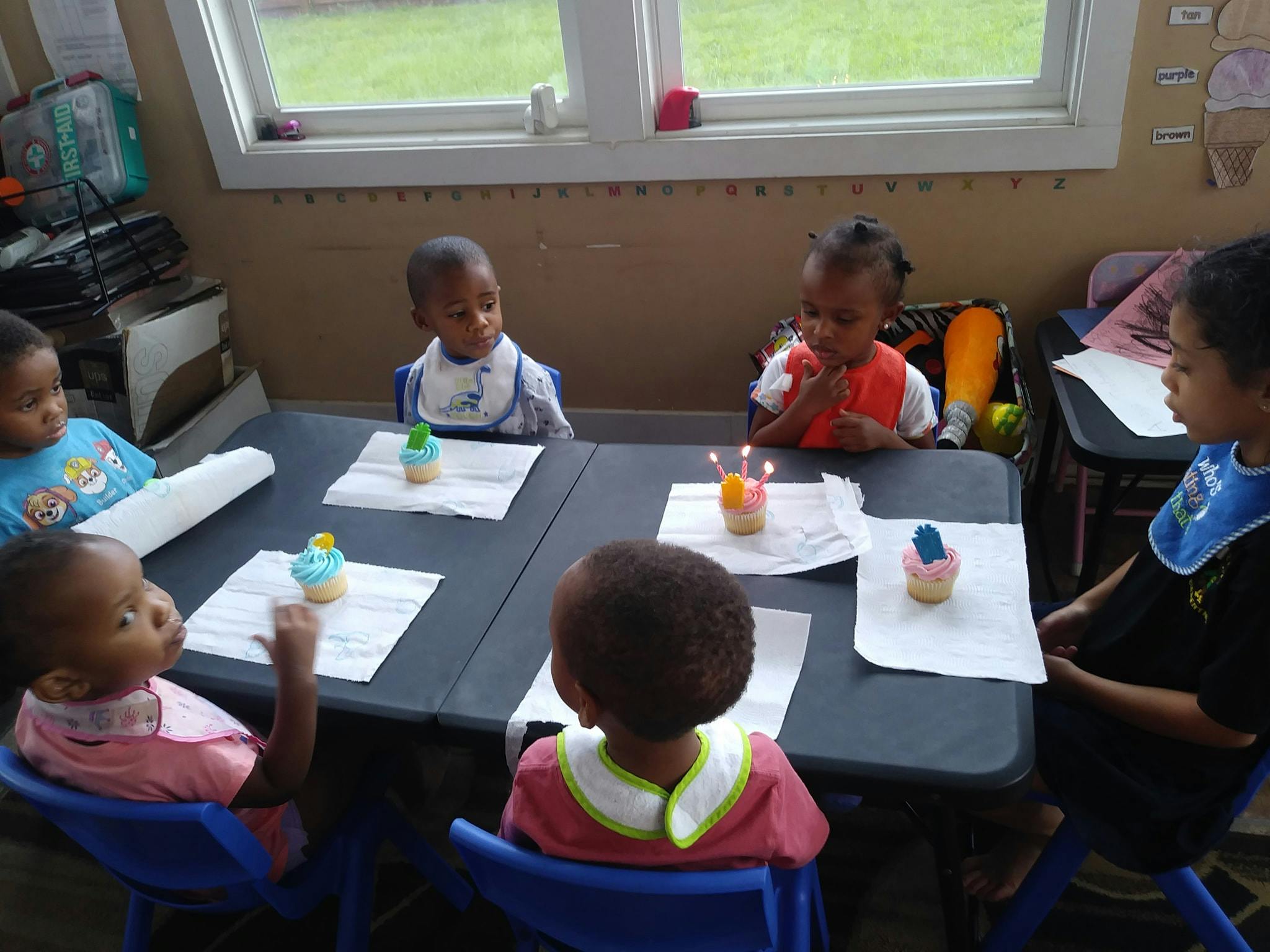 Children sitting around a table with cupcakes