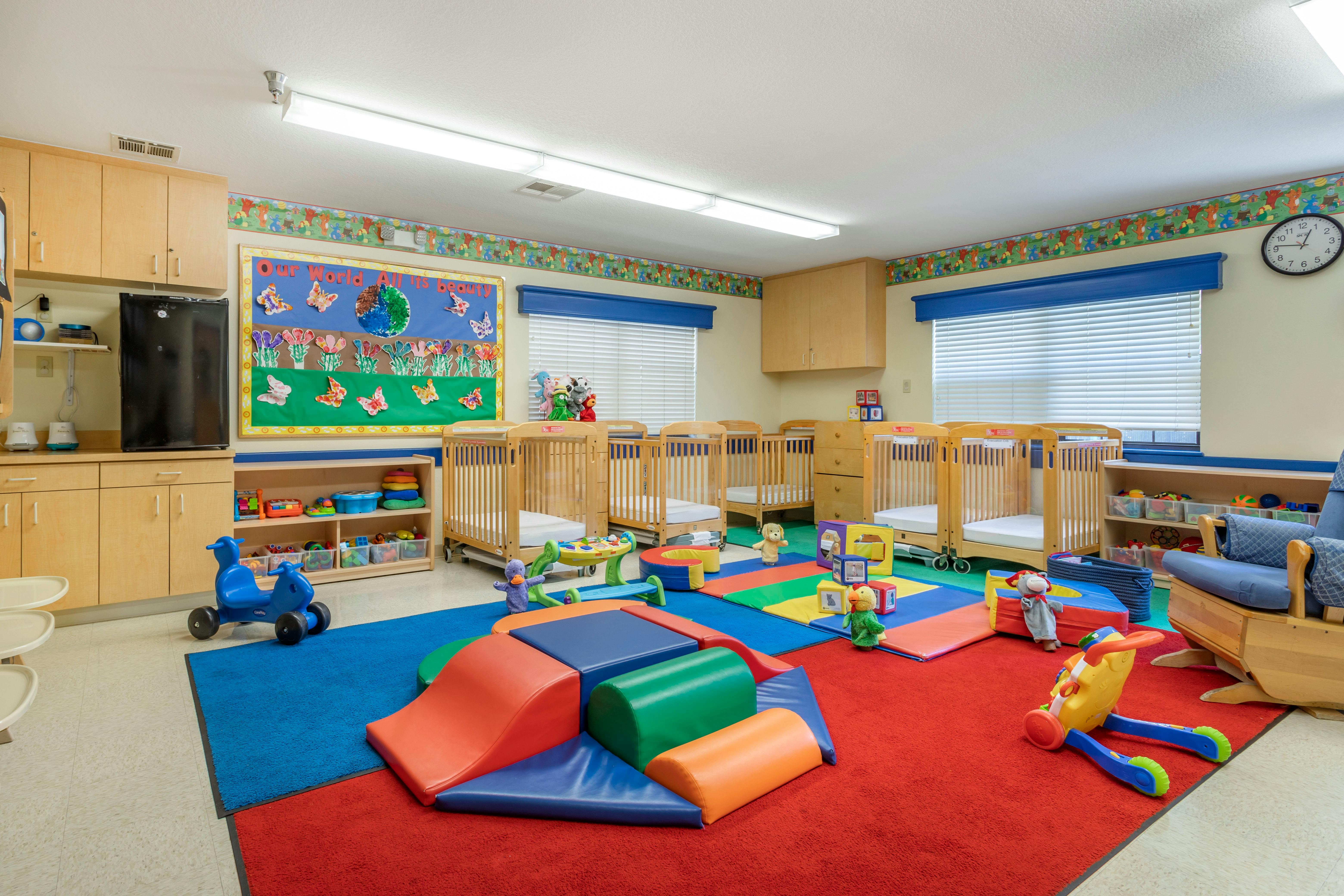 A classroom with cribs and soft play mats
