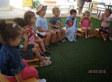 Children sitting in a circle on a green surface