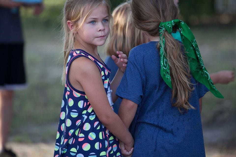 Child in polka dot dress holding hands with another child