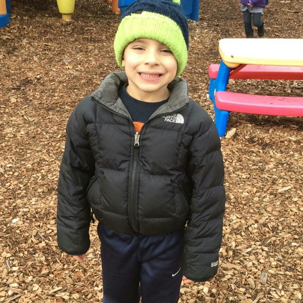 Child in a winter coat and hat smiling