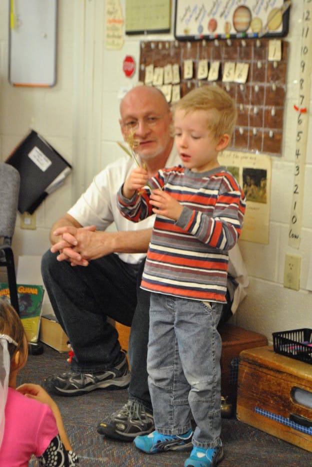 Adult and child holding a plant in a classroom