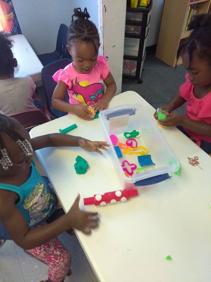 Three children playing with modeling clay at a table