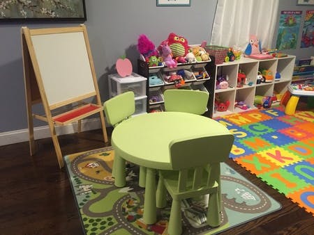 Children's play area with a small table and chairs, easel, and toy shelves