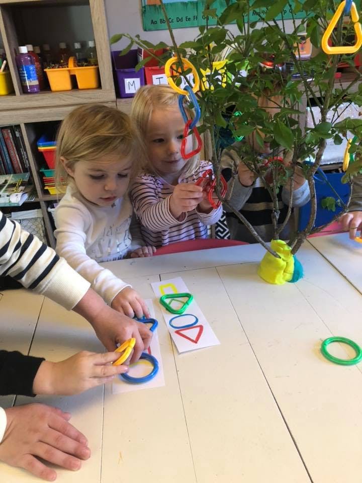 Children playing with colorful shape sorter toys at a table