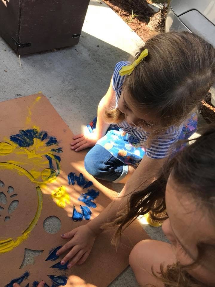 Two children painting a stencil on a board
