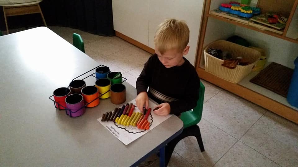Child sitting at a table coloring a picture