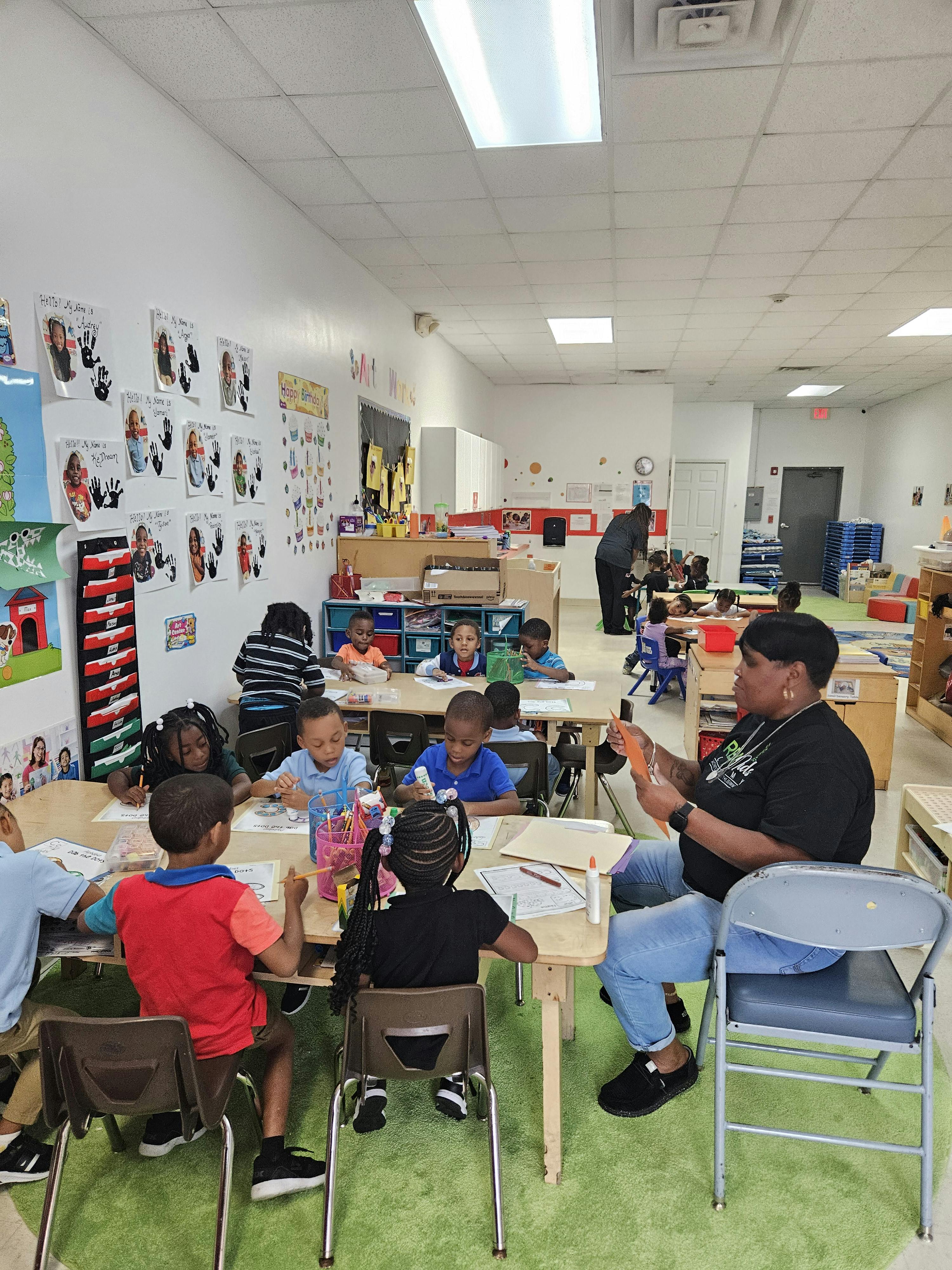Adult and children sitting at tables in a classroom