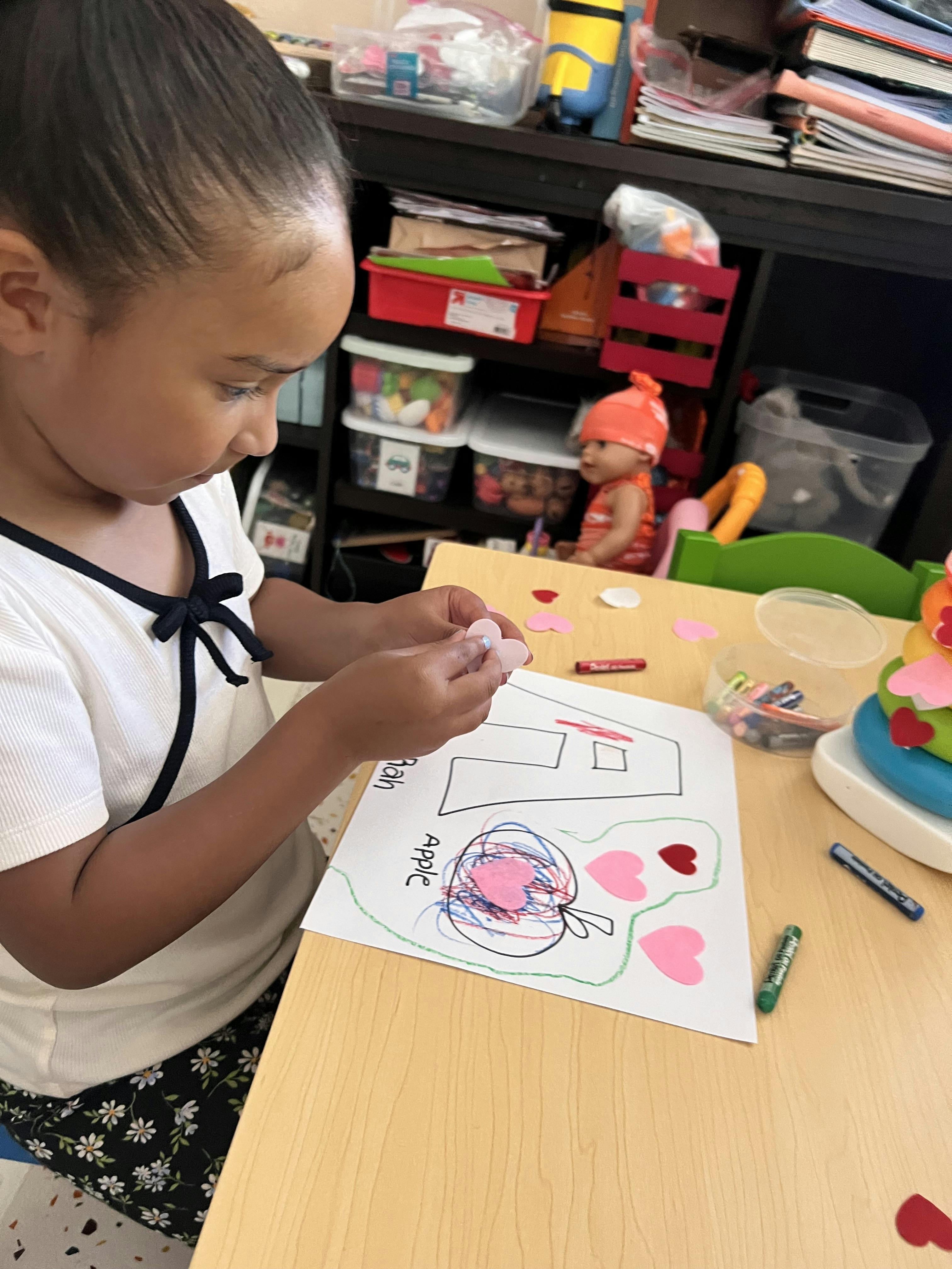 Child applying heart-shaped cutouts to a drawing