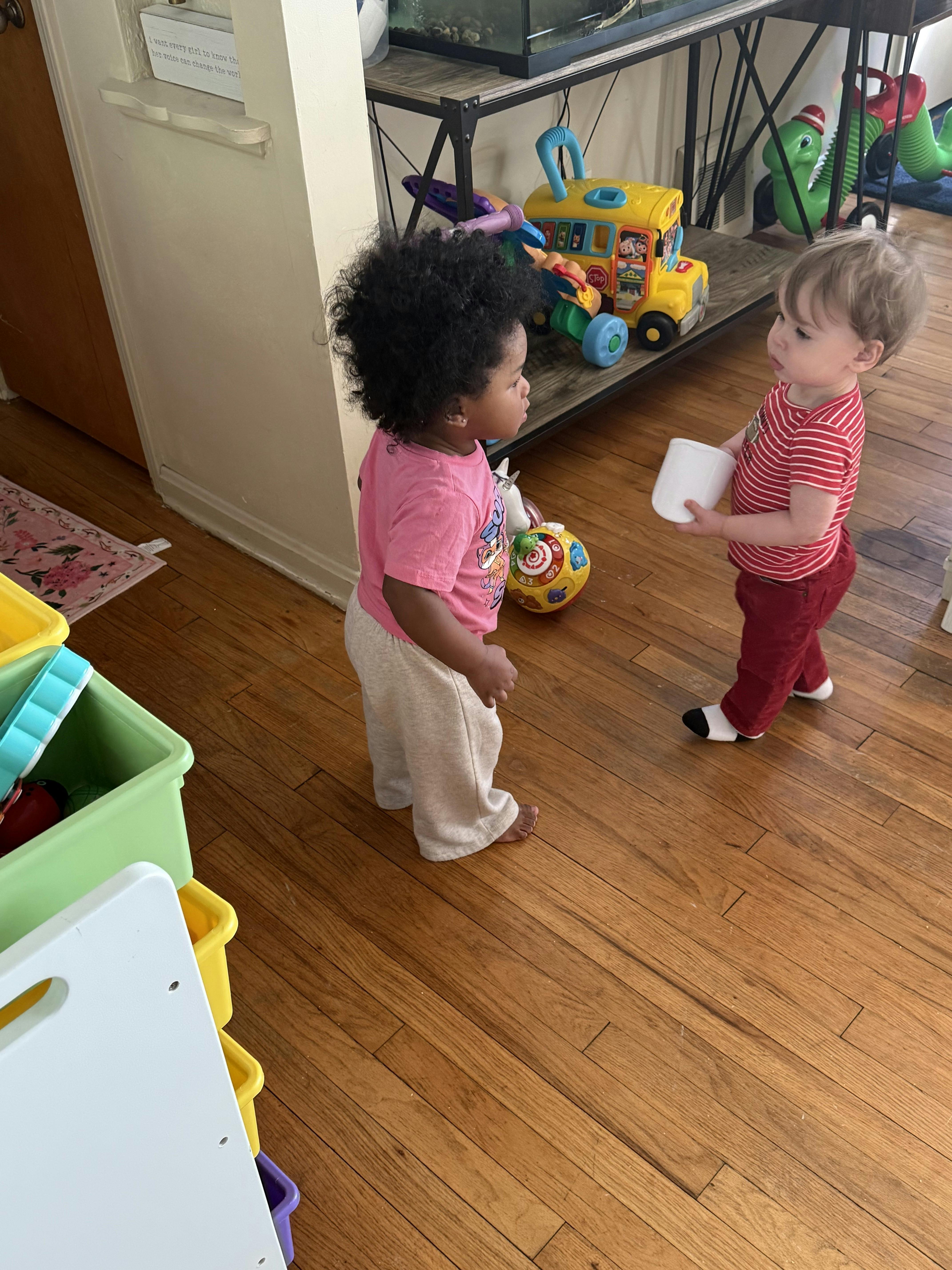 Two young children standing on a wooden floor