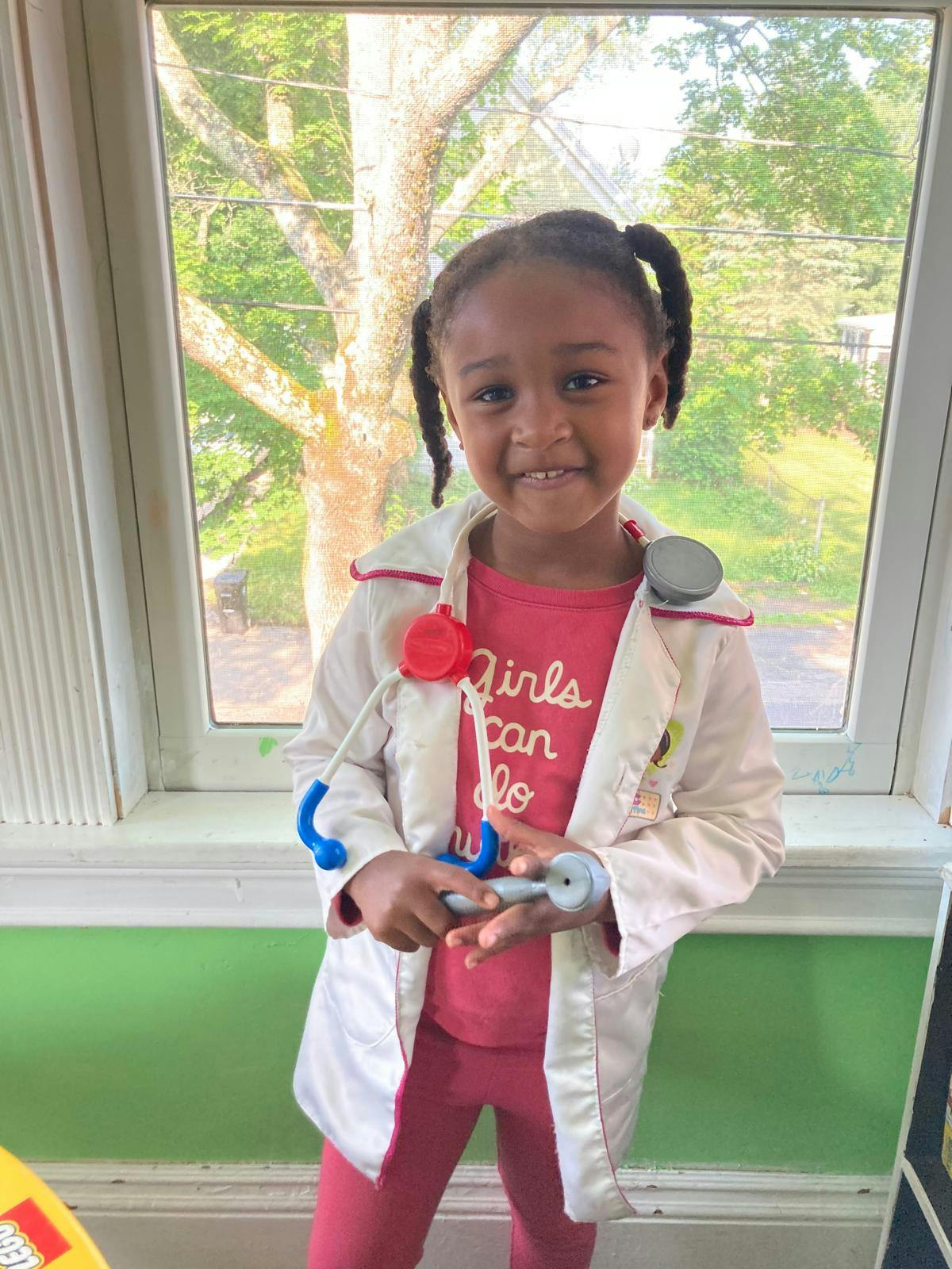 Child in a doctor's coat holding a toy stethoscope