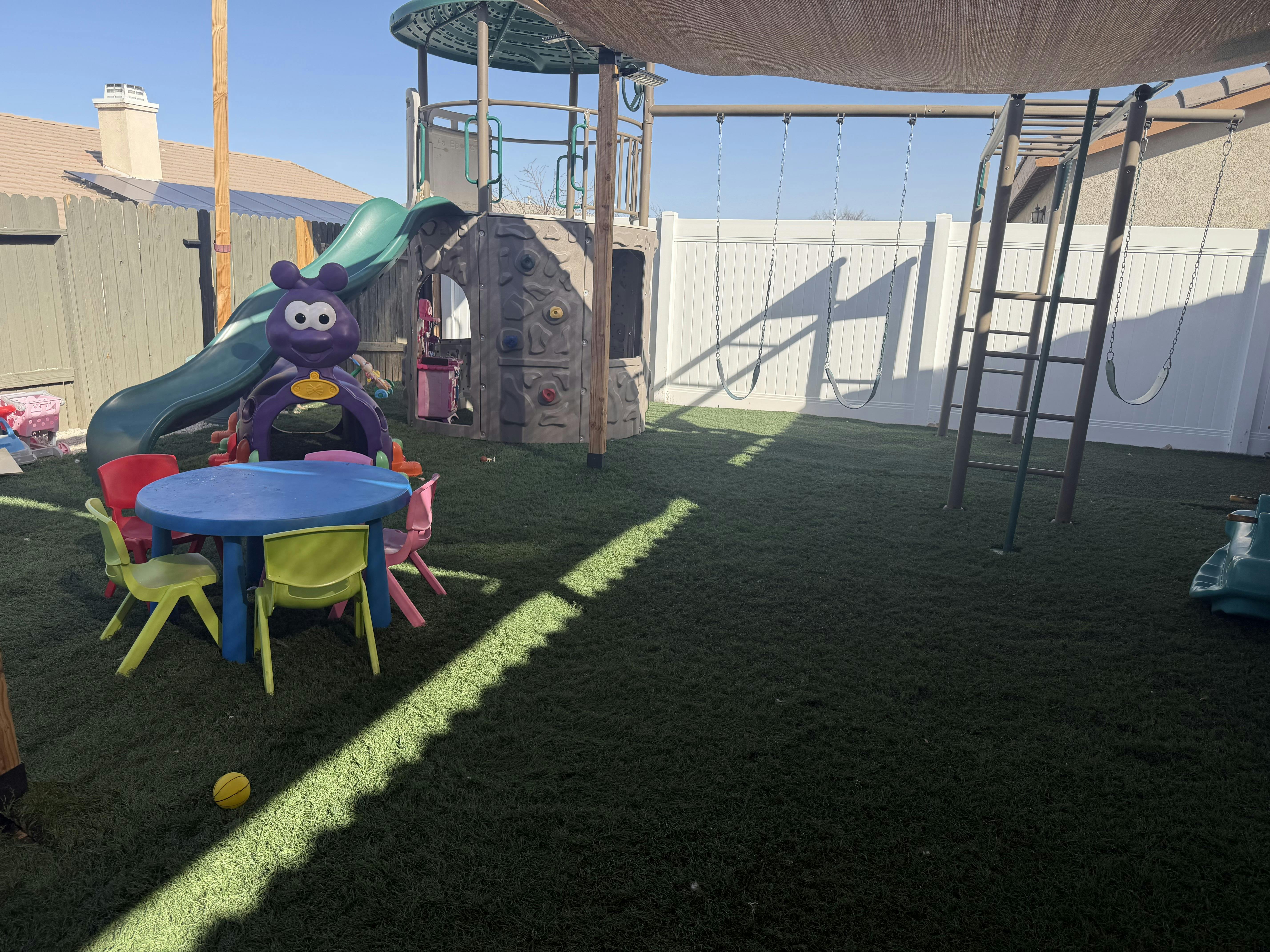 Playground area with artificial turf, a play structure with a slide, swings