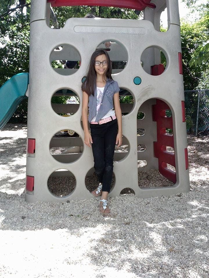 Teen standing in front of a playground structure