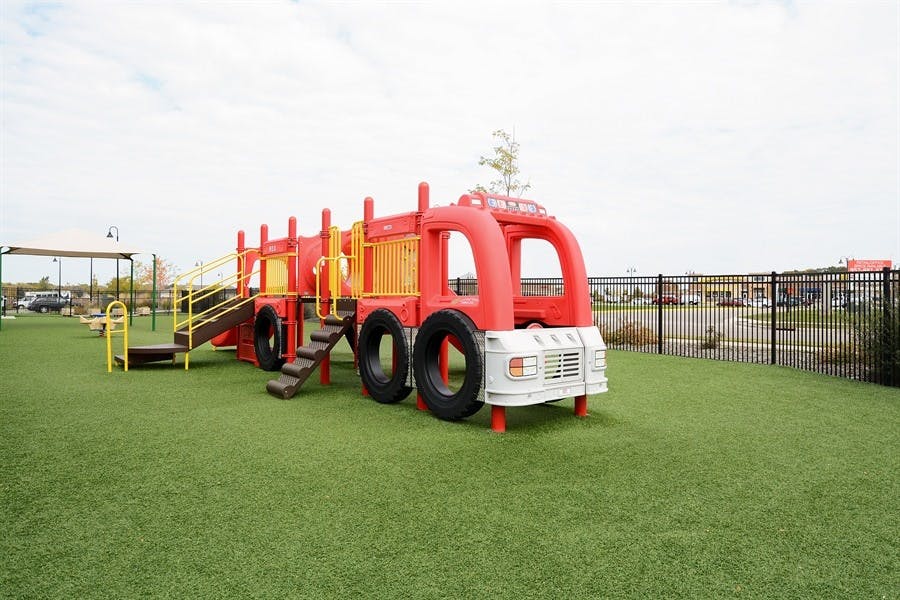 Red fire truck-shaped playground equipment on green turf