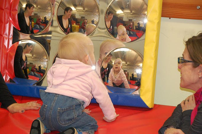 Child looking at their reflection in a funhouse mirror