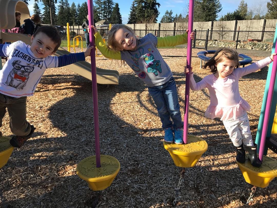 Three children standing on playground swings