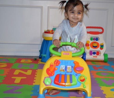 Child standing behind a colorful toy walker