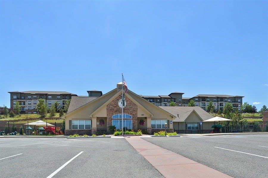 Building with a parking lot in front and apartment buildings in the background