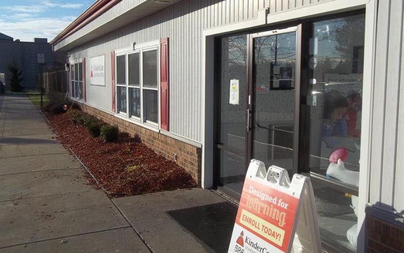 Building exterior with KinderCare sign and A-frame advertising enrollment