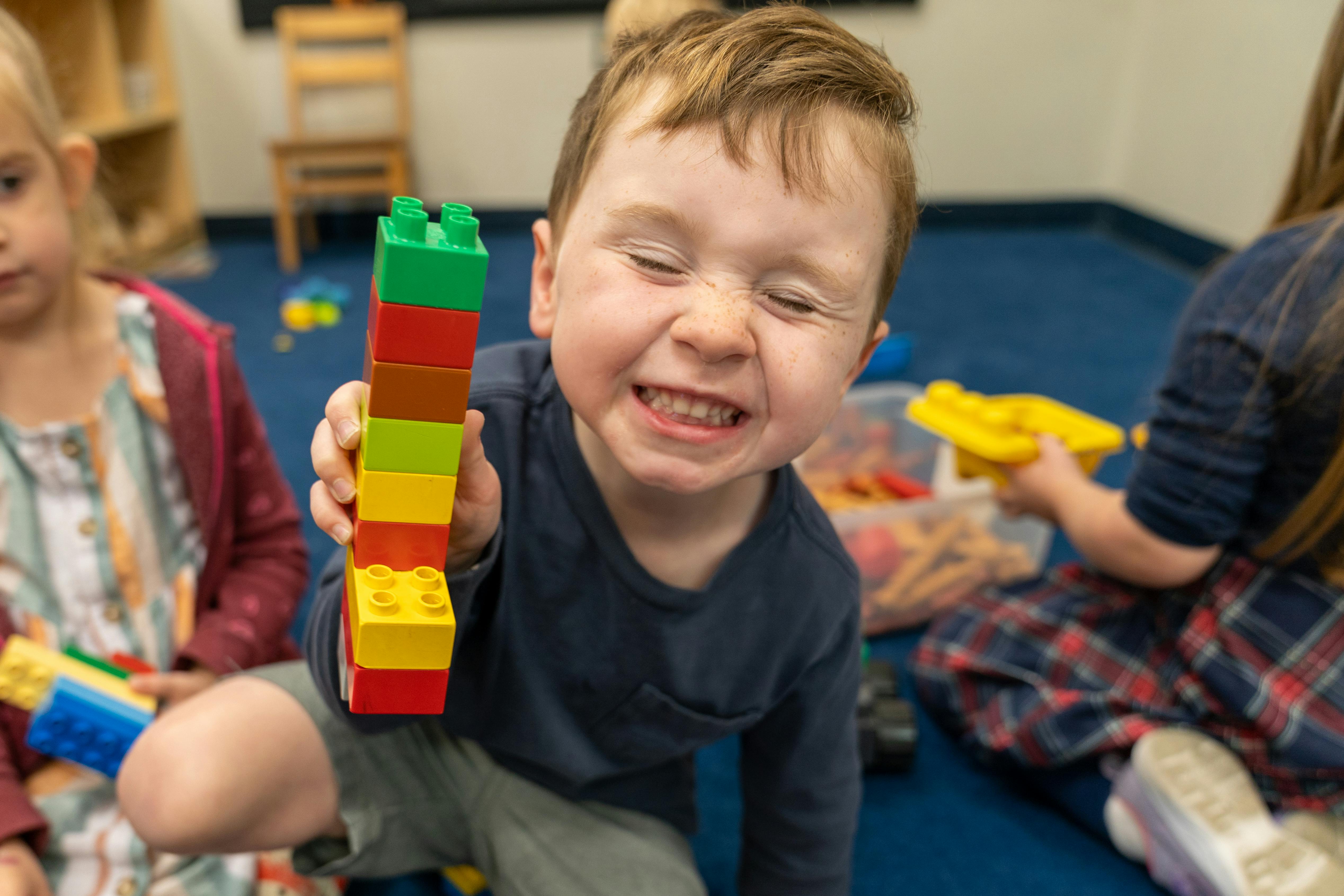Child holding up a stack of colorful building blocks