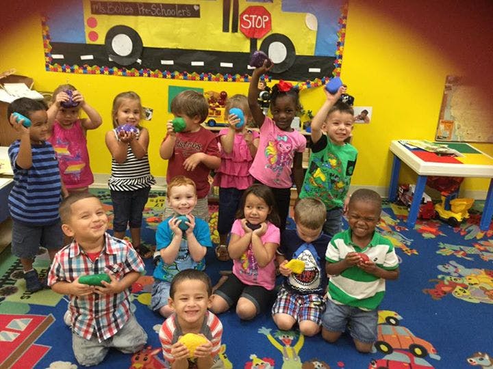 Group of children holding small objects in a classroom