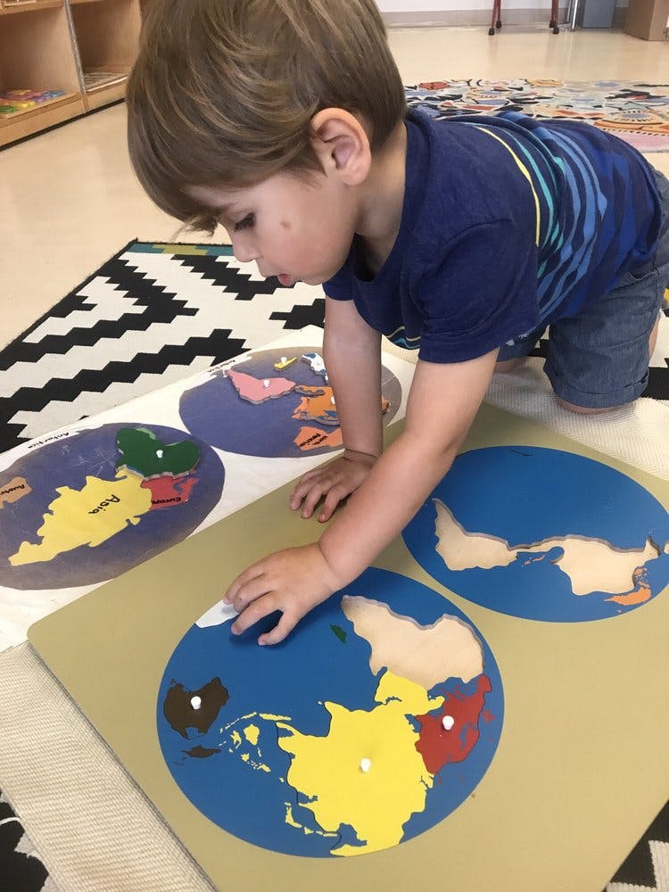 Child on knees playing with a world map puzzle
