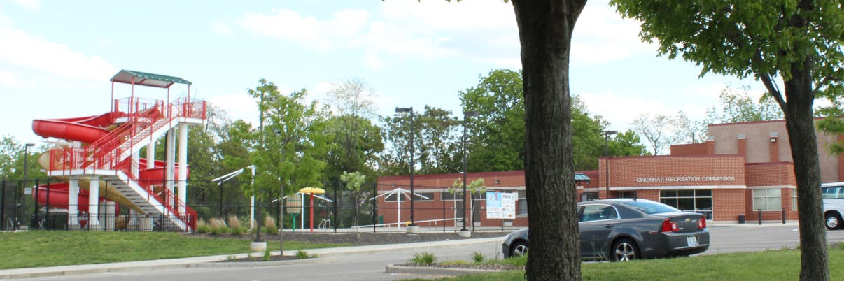 Red water slide structure next to a brick building and parked cars