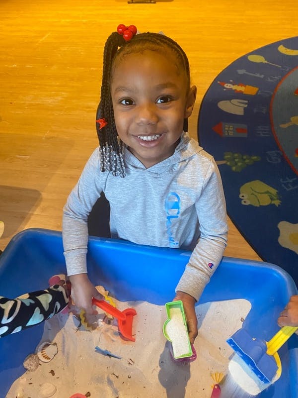 Child playing in a sand table with toys