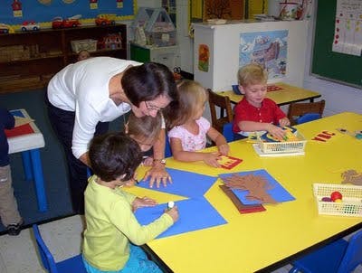Person helping children with crafts in a classroom
