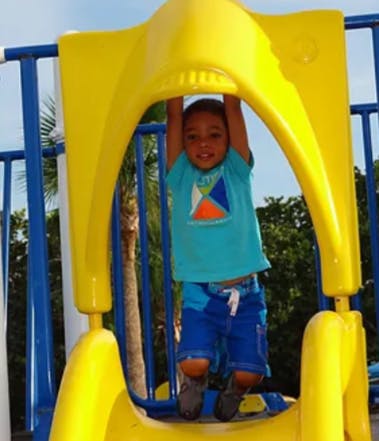 Child hanging from yellow playground equipment