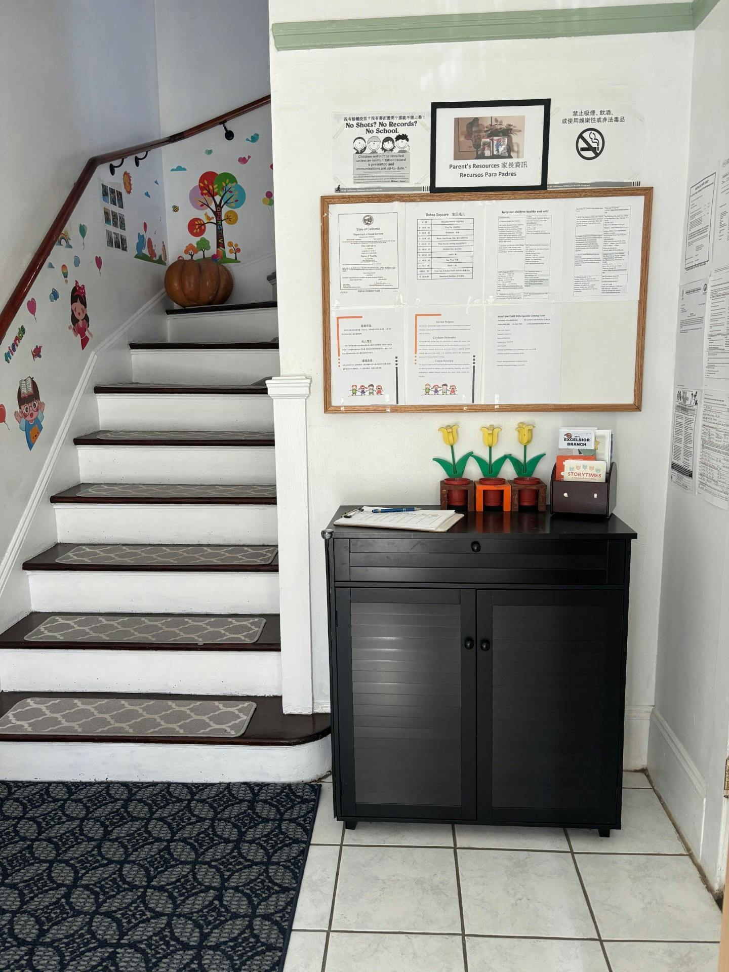 Staircase with wall decals next to a bulletin board and black cabinet