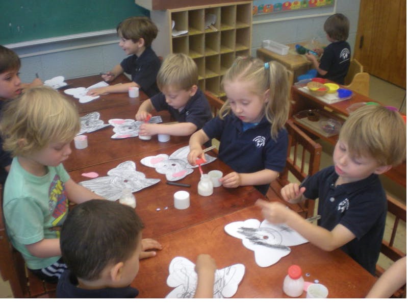 Children doing crafts at a table in a classroom